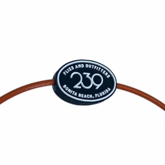 Close-up of black silicone button with raised 239 Flies text on brown cord