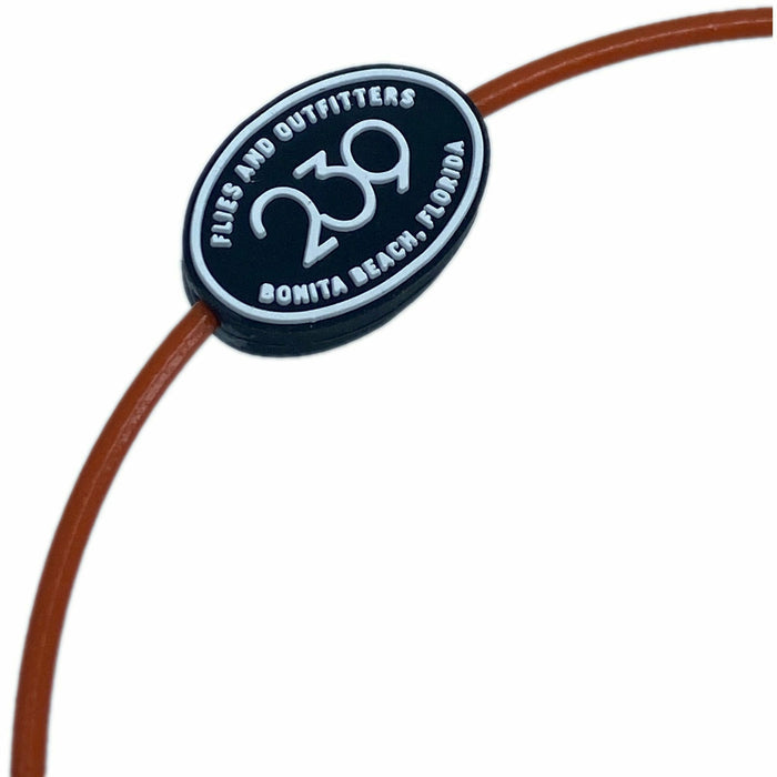 Close-up of black oval rubber emblem with raised white 239 text on brown cord