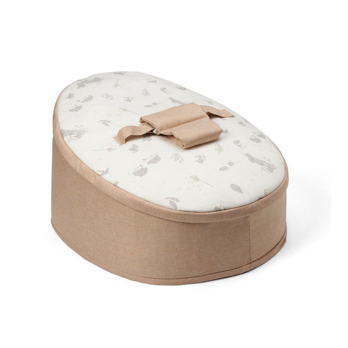 A beige baby beanbag chair featuring frolicking bunnies and delicate leaves.