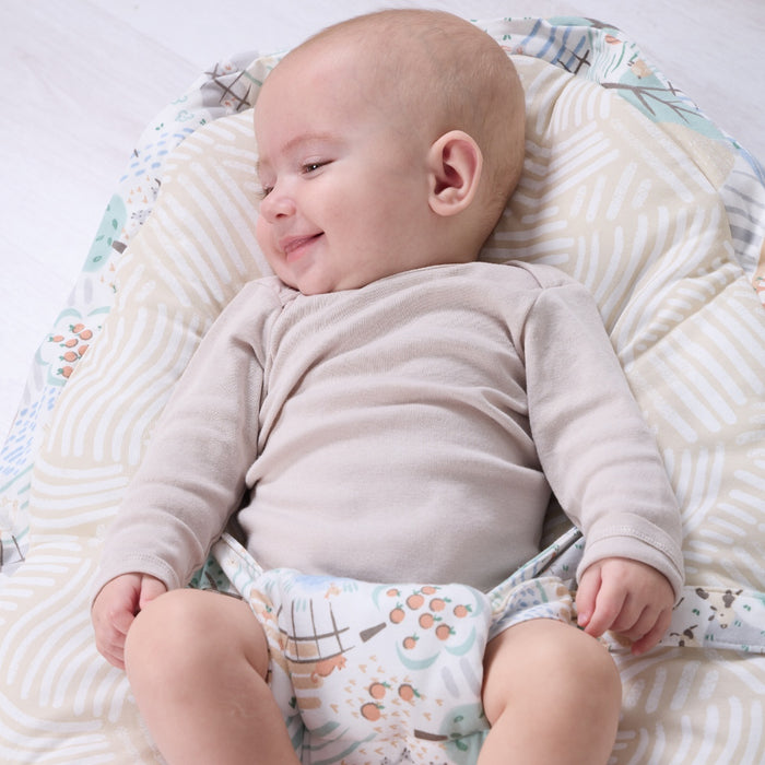 Smiling baby resting comfortably on the Good Life beanbag, showcasing soft contoured shape and calming neutral tones