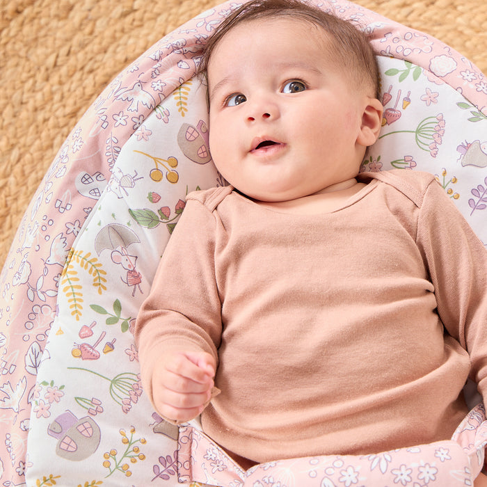 Baby resting on Tiny Tails beanbag in pastel woodland print, showing contoured support and soft, breathable cotton-blend fabric