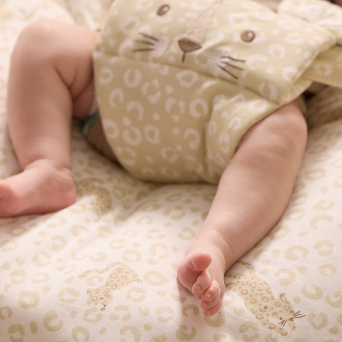 Close-up of baby’s legs resting on the Love Cats bean bag, highlighting soft leopard print fabric and smooth, cushioned surface
