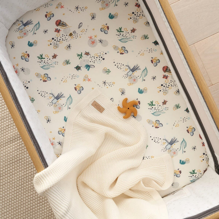 Overhead view of Our Planet bedside crib fitted sheets 2 pack, including striped and sea life print designs for playful and restful sleep