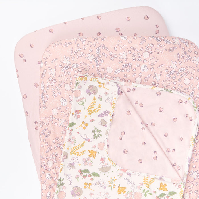 Cutout view of the Tiny Tails bedside crib starter pack featuring two floral pink fitted sheets and a reversible coverlet