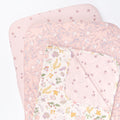 Cutout view of the Tiny Tails bedside crib starter pack featuring two floral pink fitted sheets and a reversible coverlet