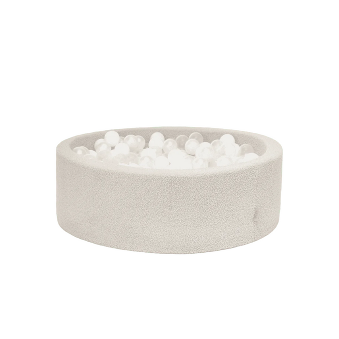 Cutout view of the Bola baby ball pit in mushroom, showcasing the rounded foam structure, boucle fabric finish and soft white balls