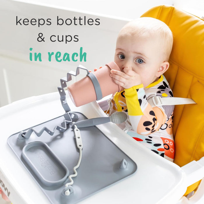 baby drinking out of cup attached with busy baby bottle bungee to busy baby original suction placemat