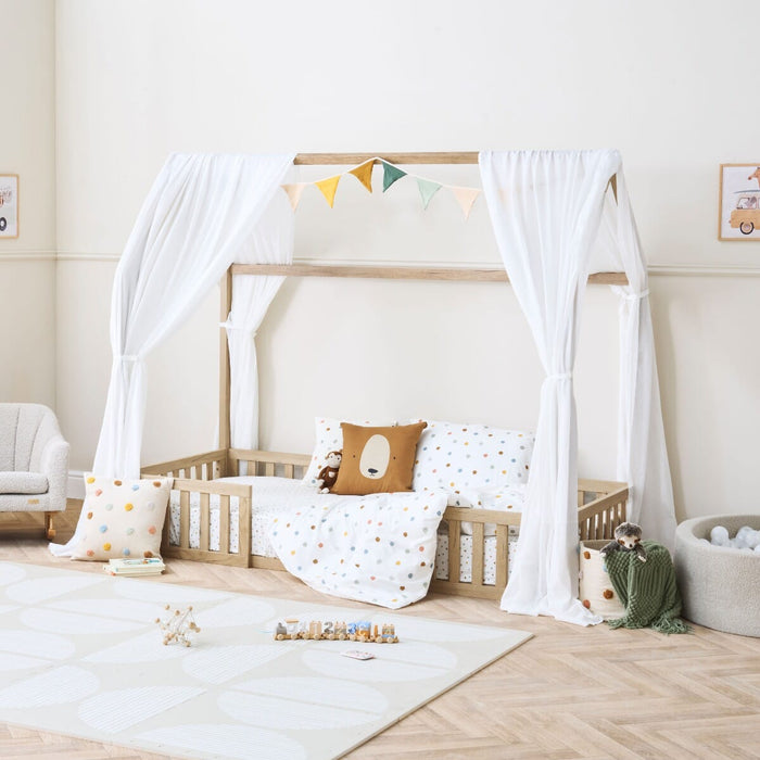 Casa Grande toddler floor bed with curtains styled in a neutral bedroom with colourful bedding and toys.