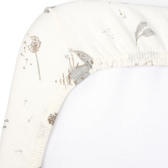 Close-up of Cocoon cot bed fitted sheet corner with elasticated edge, showing soft organic cotton fabric and delicate woodland print detail
