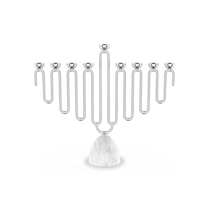 The Coluna Menorah Carrara Marble & Silver by Anna New York features a striking geometric, wavy design with eight silver branches set atop a smooth Italian Carrara marble base. Photographed against a plain white background, this modern menorah seamlessly blends contemporary style with timeless elegance.