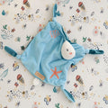 Overhead view of the Our Planet comforter on an ocean-themed sheet, highlighting its embroidered shell and starfish designs