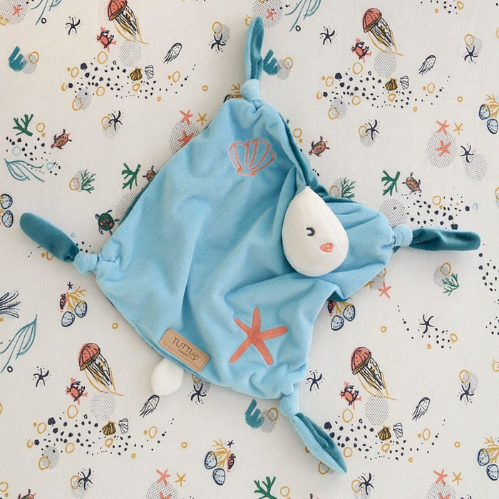 Overhead view of the Our Planet comforter on an ocean-themed sheet, highlighting its embroidered shell and starfish designs
