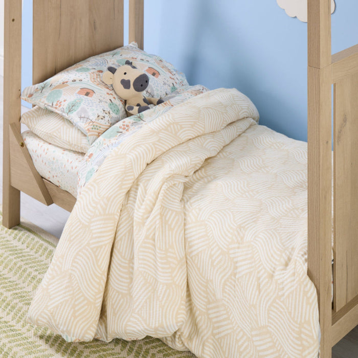 Children's bed with a patterned duvet and pillow against a light blue wall.