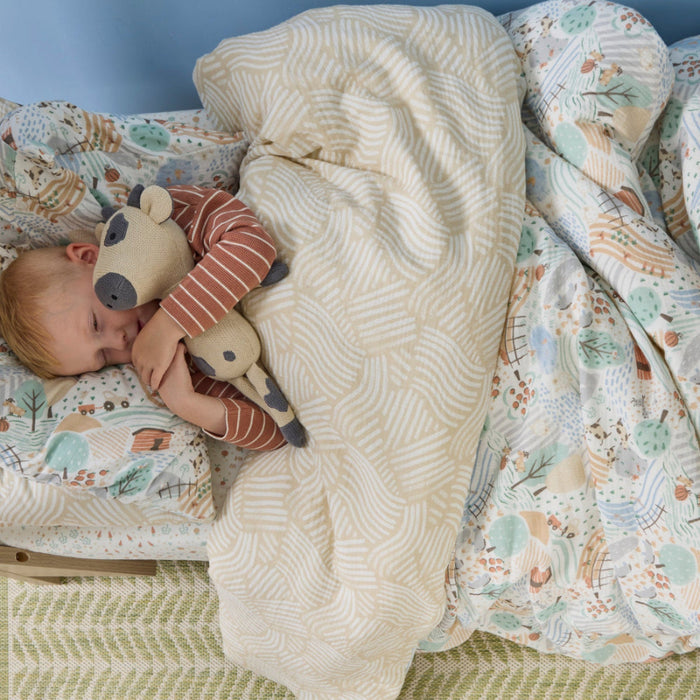 Child sleeping in a bedwith a patterned comforter and plush toy