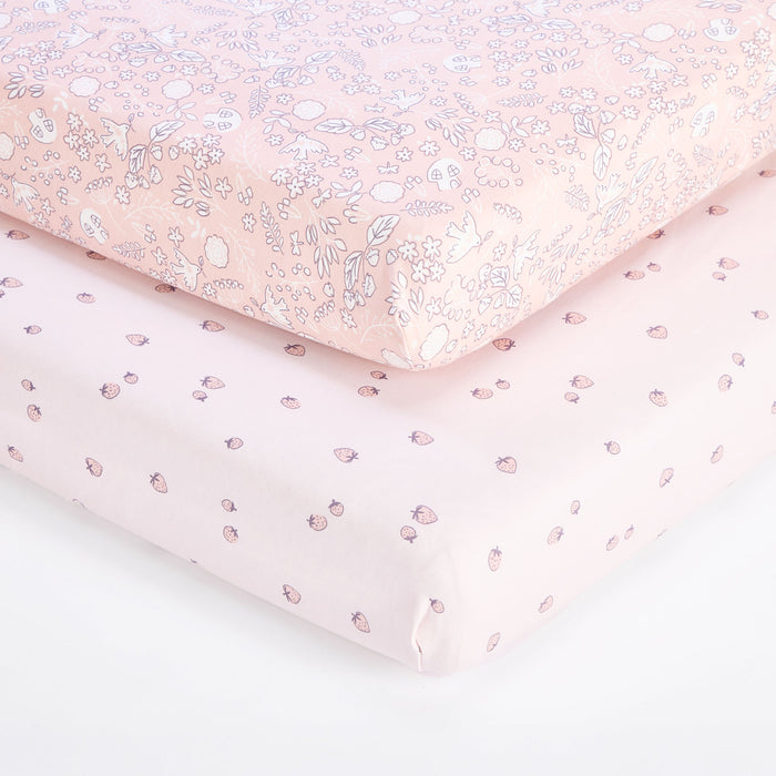 Close-up of tiny tails cot bed fitted sheet layered over strawberry print sheet, showing elasticated corners and smooth fit.