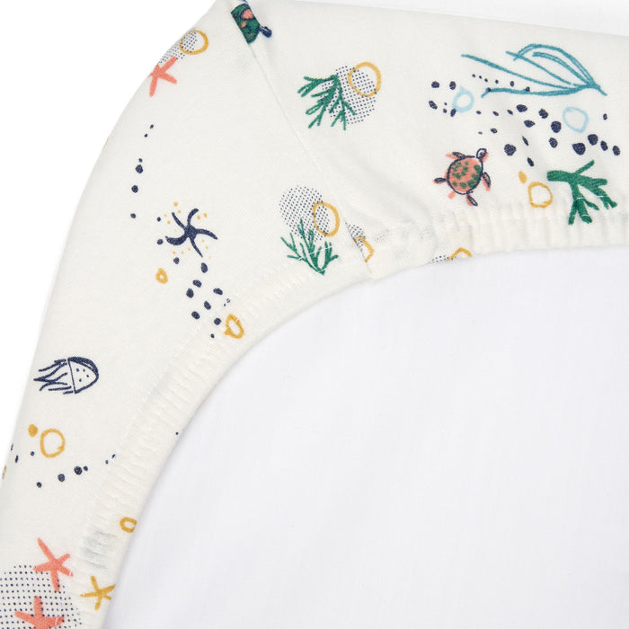 Close-up of Our Planet bedside crib fitted sheet in organic cotton, showing elasticated corner with playful sea life print detail