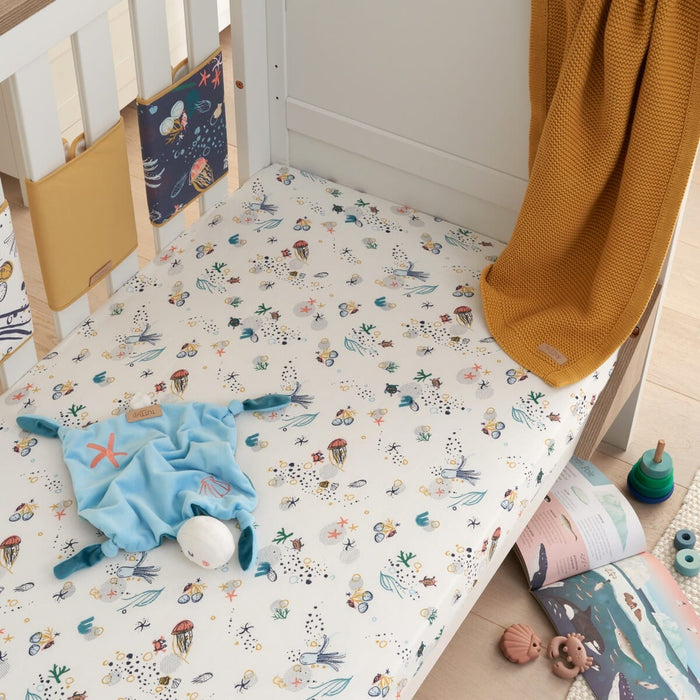 Lifestyle view of cot fitted sheet in Our Planet design, ocean-themed cotton fabric creating a snug, playful and calming nursery space