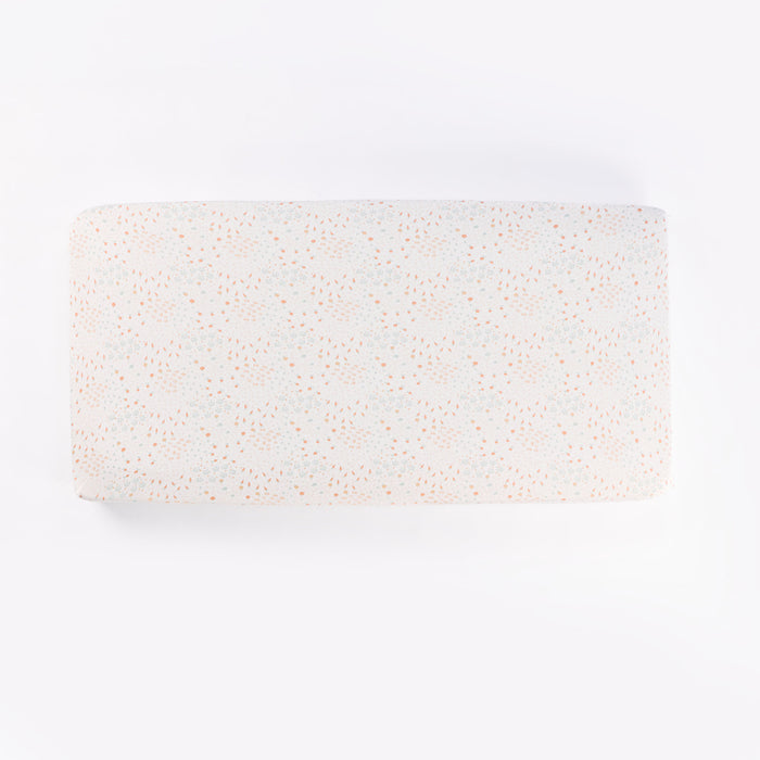 Cutout of Good Life cot fitted sheet in cream with soft scattered print of pastel florals and abstract dots, made from breathable cotton