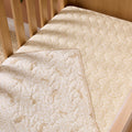 Love Cats cot bed coverlet styled inside wooden cot, featuring reversible beige animal print and soft quilted finish for cosy comfort.