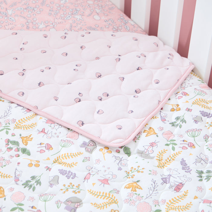 Reversible cot bed coverlet with floral print on one side and strawberries on the other