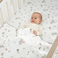 Baby tucked under Cocoon coverlet, quilted cotton with woodland animal prints providing warmth, comfort and a safe sleep layer