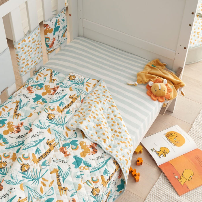Lifestyle view of Run Wild coverlet on cot, reversible quilted cotton with playful jungle prints for comfort and colourful nursery charm
