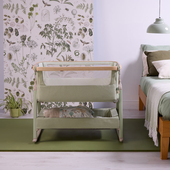 Front view of the CoZee Air 2 bedside crib in eucalyptus, styled beside the bed with mesh panels and integrated storage shelf.