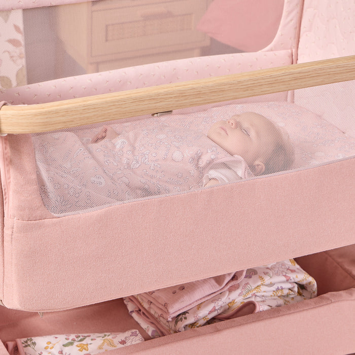 Close-up of the CoZee Air 2 bedside crib in blush, showing breathable mesh sides for improved airflow and clear visibility of baby.