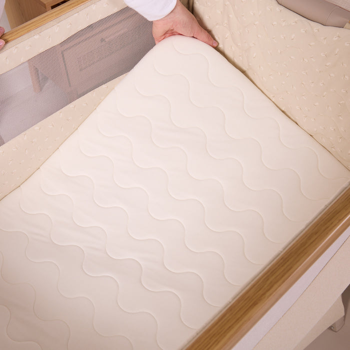 Top view of the CoZee Air 2 bedside crib in toasted oak/sand showing the breathable mattress fitting neatly within the padded sleep space.