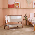 CoZee bedside crib in Scandinavian walnut and ecru styled in a modern bedroom, with mesh panel and handy under-crib shelf