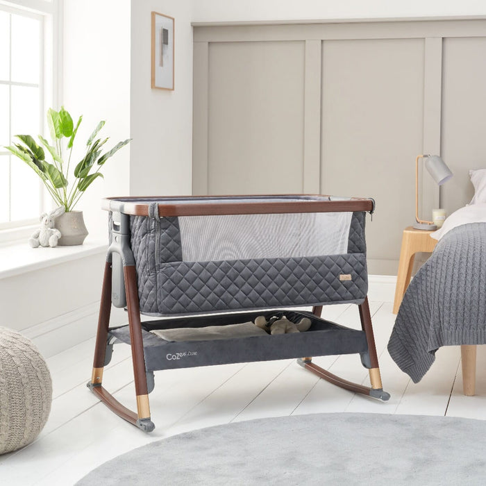 Room view of the CoZee Luxe crib in walnut and slate with rocking bars, blending quilted fabric with smooth rocking function