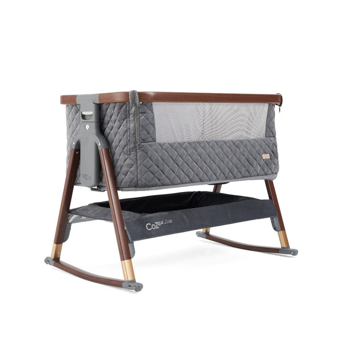 Angled view of the CoZee Luxe crib in walnut and slate with rocking bars for gentle motion and easy-access underbed storage