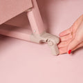 Close-up of the CoZee Air 2 bedside crib brake being engaged by hand, showing the locking castor for added stability and safety.