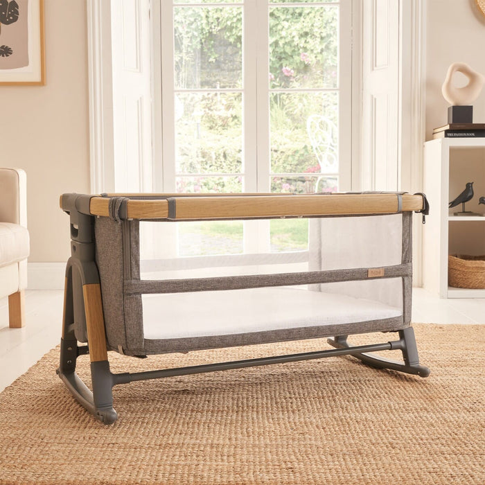 CoZee bassinet in oak and charcoal set in a bright nursery, shown in rocking mode for gentle motion and cosy sleep