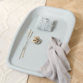Lifestyle view of the Cushi baby changing mat in cloud grey, styled with blanket and toy, showing practical cot-top changing design