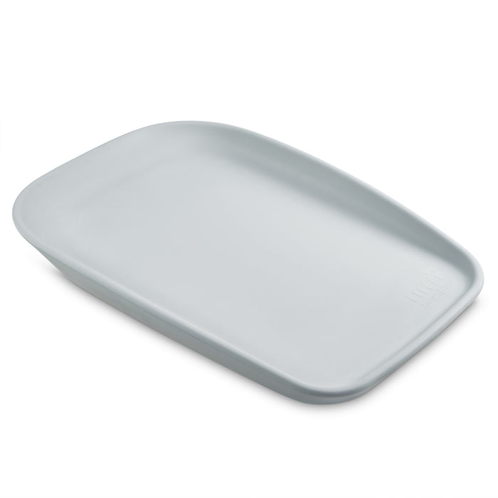 Angled view of the Cushi mini baby changing mat in cloud, highlighting its slim profile, ergonomic shape and softly curved sides.