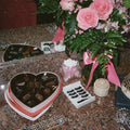 Close-up of a heart-shaped chocolate box a bouquet of pink roses false eyelashes and a crown on a bust