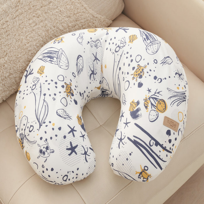 Curved feeding pillow in Our Planet print, featuring soft supportive shape and illustrated ocean-inspired pattern, styled on a neutral sofa.