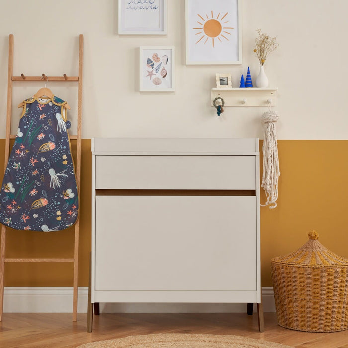 Fuori chest changer with white sand and warm walnut colours, featuring handleless slow-close drawers and exposed legs