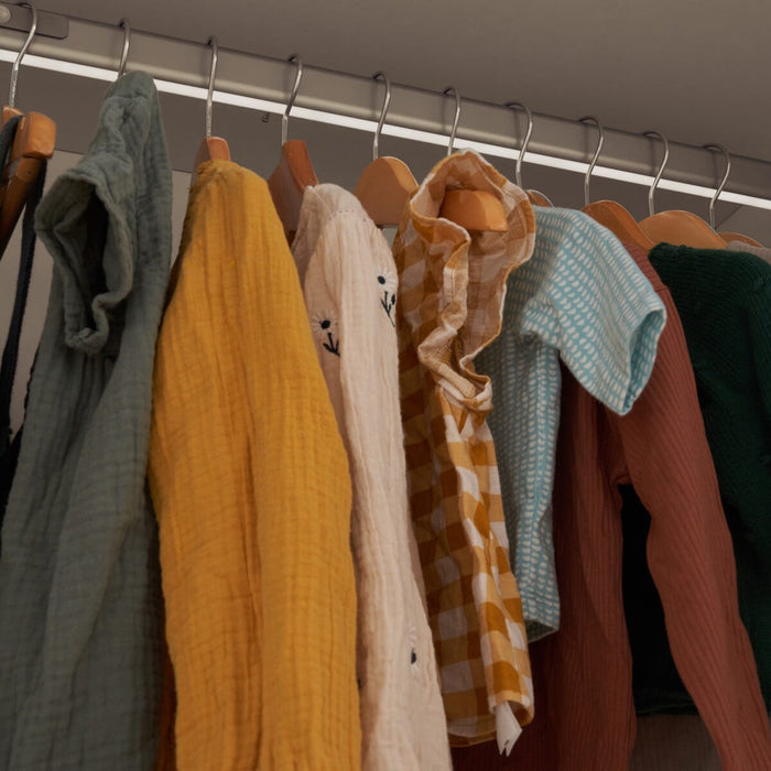 Close-up of wardrobe hanging rail with integrated LED light and hanging clothes