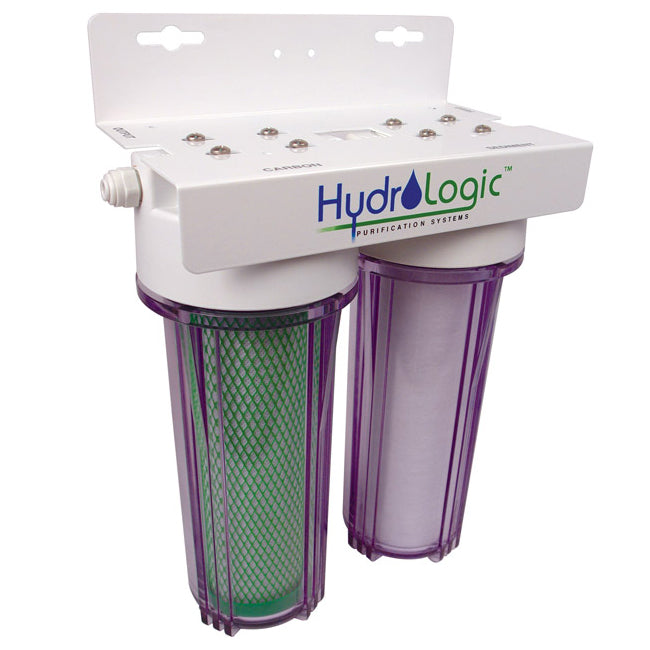 A two-stage water purification system with clear purple housings and a white top labeled "TAS Purification Systems." The left chamber uses KDF85 filtration media in the green filter, while the right features a white filter. This device, known as the Hydrologic Small Boy Dechlorinator & Sediment Water Filter, ensures optimal water cleanliness.
