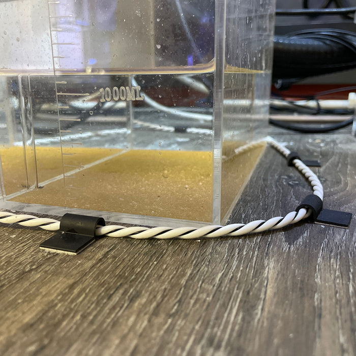 A plastic container with a small amount of water in it, equipped with a TAS HYDROS Rope Leak Detection Extension Cable controller.