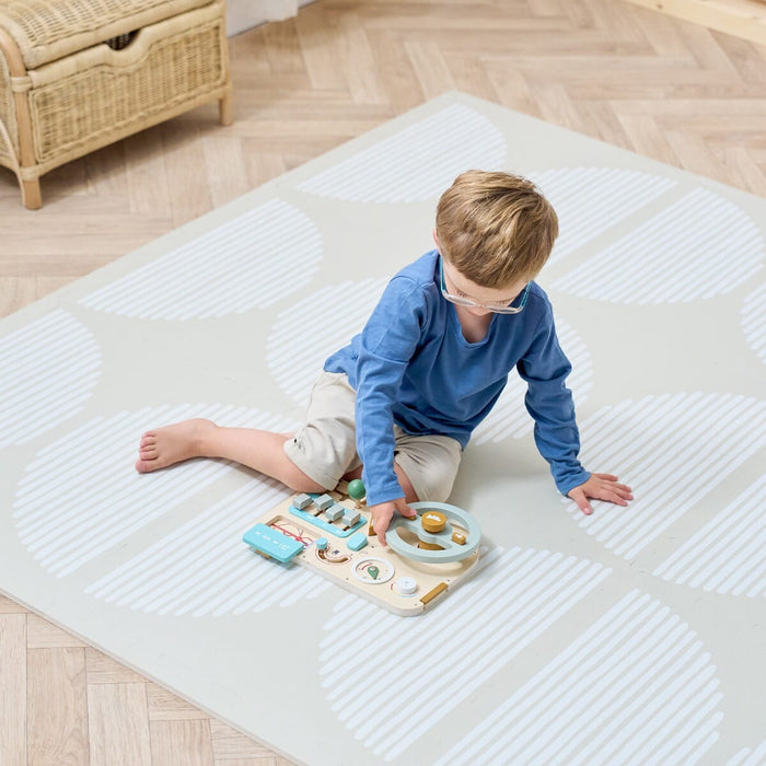A young child playing with toys on a beige playmat with a subtle pattern.