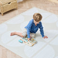 A young child playing with toys on a beige playmat with a subtle pattern.