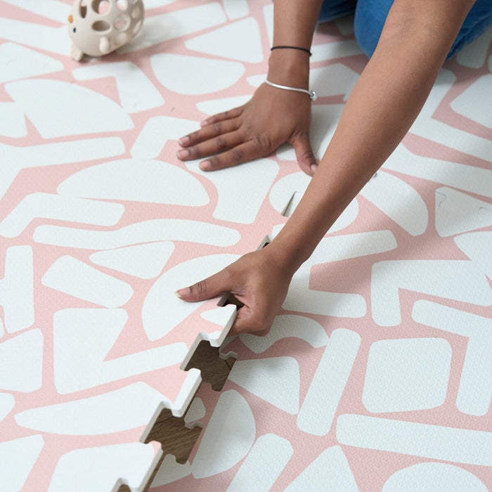 Detailed view of the Infinity Playmat Oddity Blush edges with a hand connecting the pieces.