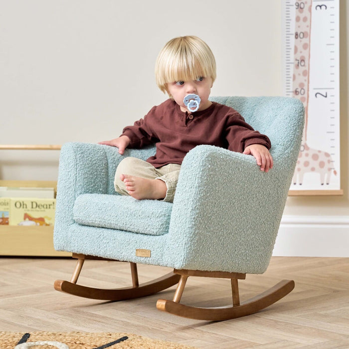 Toddler sitting in the Jonah Mini Me rocking chair in Ocean Stone, showcasing the comfortable seat height and relaxed arm support