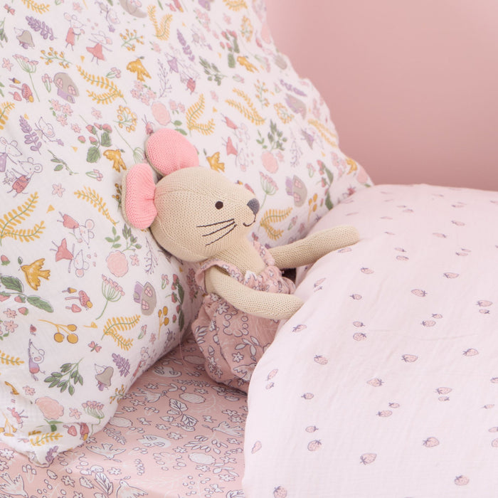 Margot Mouse knitted toy on a floral-patterned pillow with a pink background