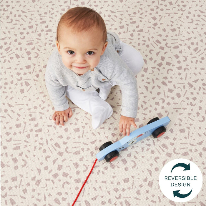 Baby sits on the terrazzo side of the reversible play mat, its cushioned surface offering a comfy, patterned area for early play