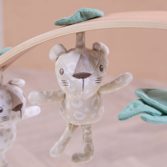 Detailed view of Love Cats muslin character toy suspended from smooth wooden play gym arch with sage leaf accents.