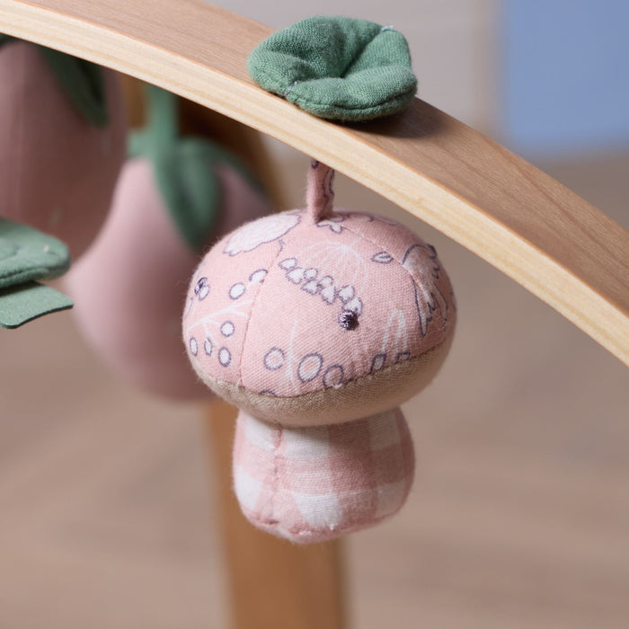 Close-up of soft pink mushroom hanging toy with embroidered details on natural wooden playgym arch.